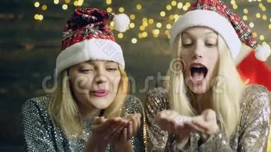 两个女孩戴着`顶<strong>帽</strong>子，把他们的手掌上的雪吹掉了。 <strong>新年</strong>`心情。 庆祝<strong>新年</strong>的概念。 二.